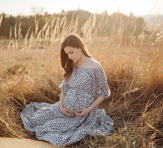 Jeune femme enceinte assise dans un champ